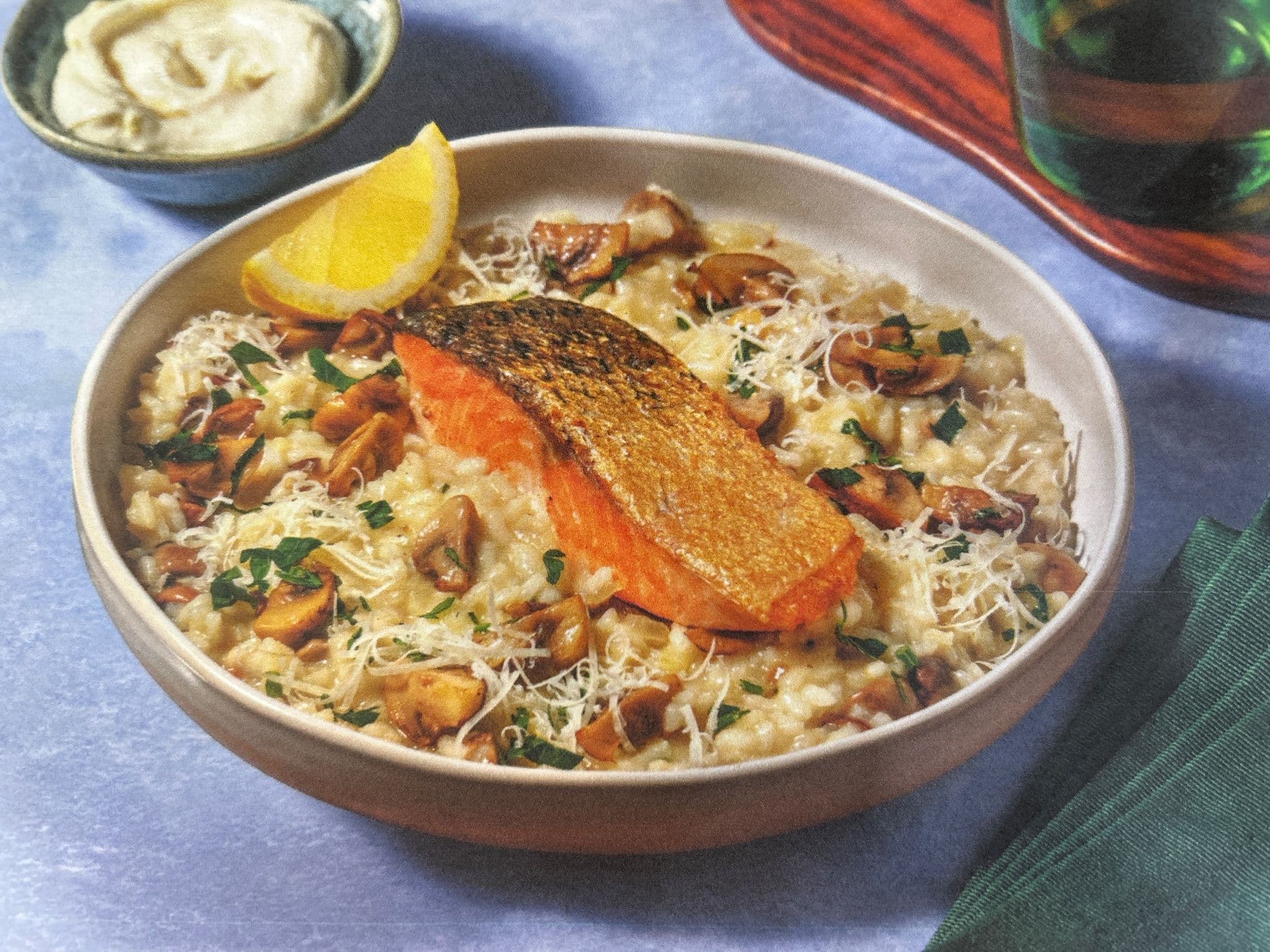 Assiette de risotto crémeux aux champignons, filet de saumon snacké peau dorée, fromage râpé et persil ciselé